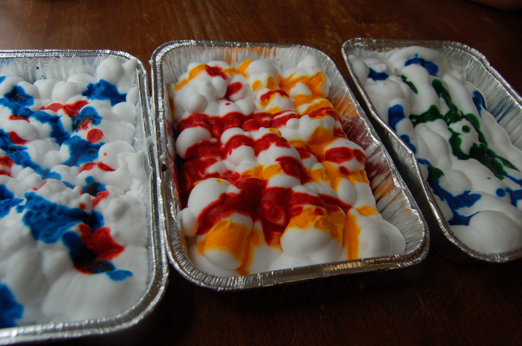 Food coloring gets dripped on top of a layer of shave cream.