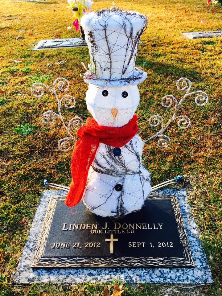 A child's grave marker with a snowman decoration on it.