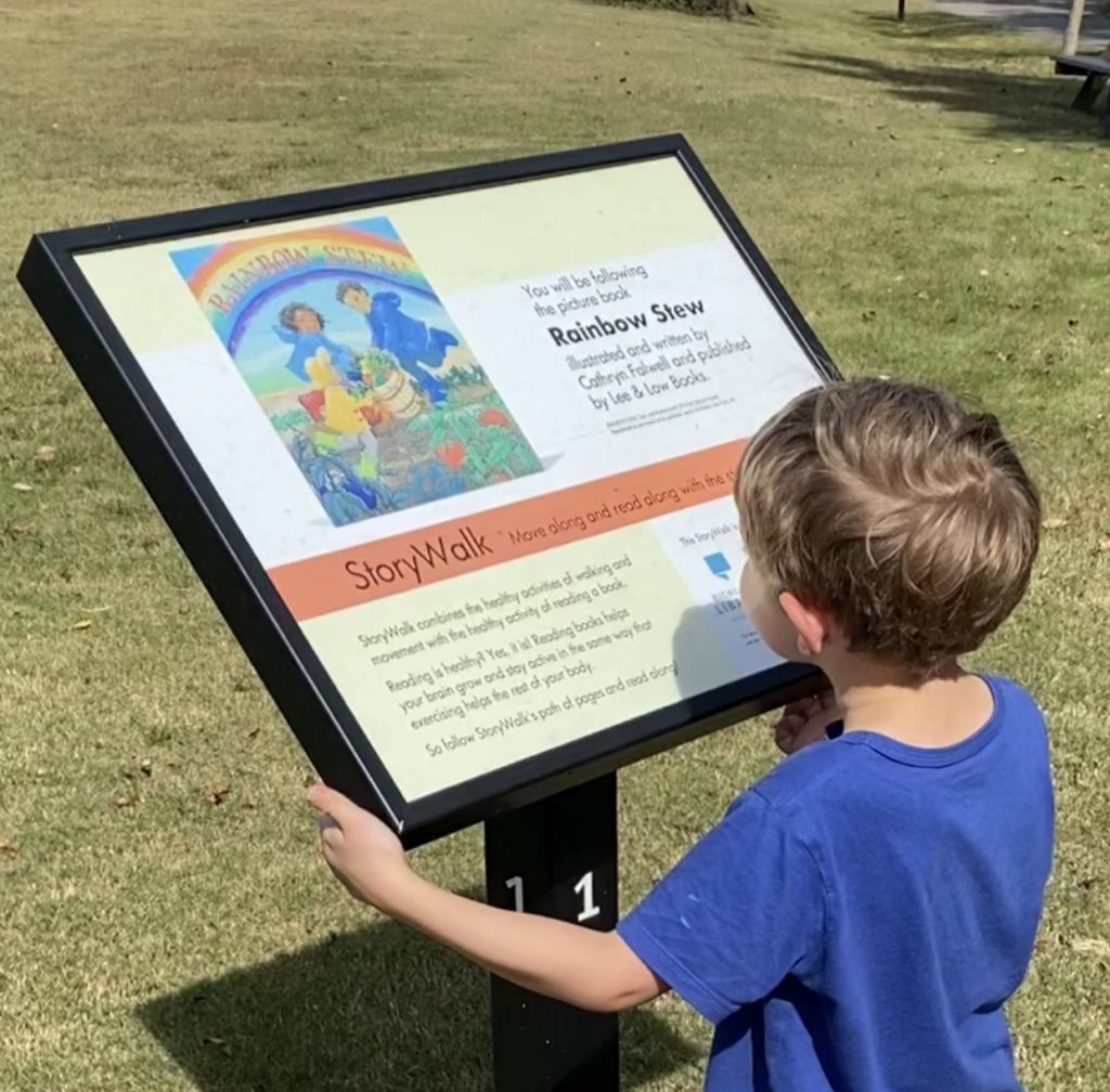 Little boy looking at first page of Doko park story walk book